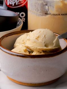 a bowl filled with ice cream sitting on top of a table next to a cup