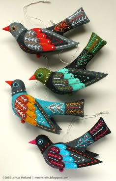 three colorful birds sitting on top of a white table next to each other and string