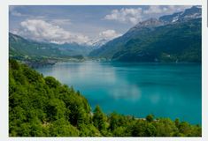 a lake surrounded by green trees and mountains