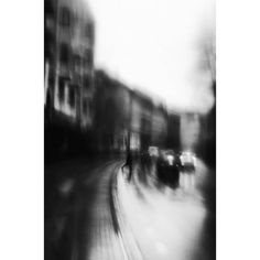 blurry photograph of people walking down the street on a rainy day with buildings in the background