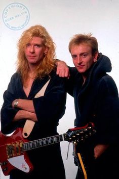 two men standing next to each other holding guitars