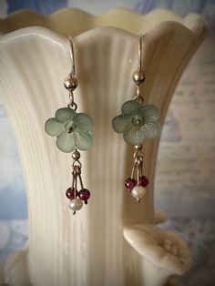 Dainty muted sage green flower beads are accented with tiny garnet beads and freshwater pearls dangling below for a whimsical look. The earrings measure 1.5 inches in total length from the top of the sterling silver ear wire to the lowest dangle. The flower bead measures 3/8 inches across. The earrings are lightweight and easy to wear....super cute! FREE Domestic US Ground shipping!! Sage Green Jewelry, Muted Sage Green, Crafts 2024, Whimsical Earrings, Garnet And Pearl, Sage Green Flowers, Muted Sage, Green Jewelry, Pretty Jewelry