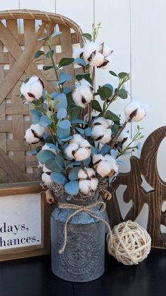 a vase filled with cotton sitting on top of a table next to a wooden sign