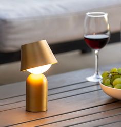 a table with a bowl of grapes and a glass of wine on it next to a lamp