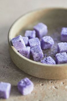 a bowl filled with purple sugar cubes on top of a table