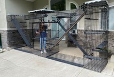 a woman is standing in front of a caged area with stairs and railings