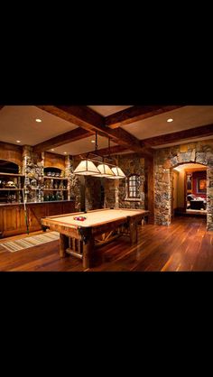 a pool table is in the middle of a room with wood flooring and stone walls