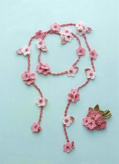 a pink crocheted necklace with flowers on it