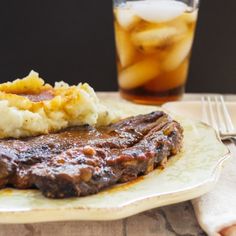 steak, mashed potatoes and gravy on a plate next to a drink