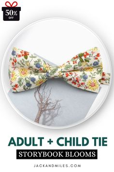 A light-colored fabric bow tie adorned with colorful flowers and leaves, placed atop a muted background featuring a tree illustration.