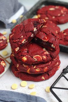 red velvet cookies are stacked on top of each other with white chocolate chips scattered around them