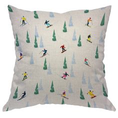 a white pillow with skiers and trees printed on the front, along with green pine trees