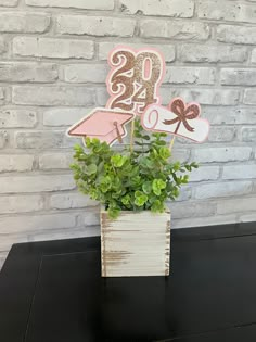 a wooden block with some plants in it on a table next to a brick wall