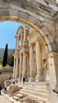 people are walking up and down the steps in front of an old building with columns