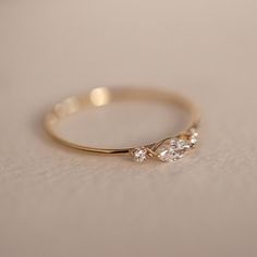 a gold ring with three diamonds on it sitting on a white tableclothed surface