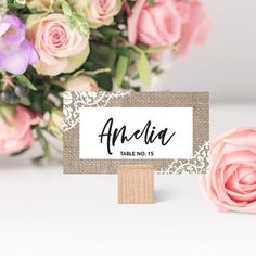 a bouquet of flowers sitting next to a table name sign on top of a wooden stand