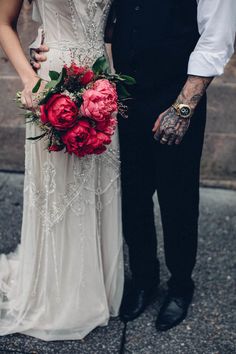 two people standing next to each other holding flowers