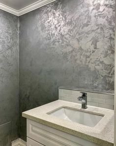 a white sink sitting under a bathroom mirror next to a wall mounted faucet