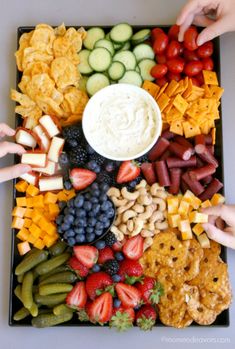 a platter filled with fruit, crackers and vegetables