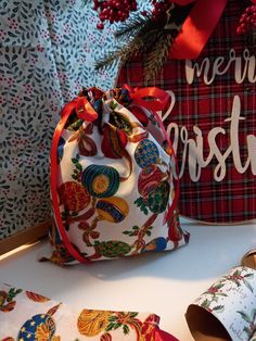 two bags with christmas designs on them are sitting next to some wrapping paper and decorations