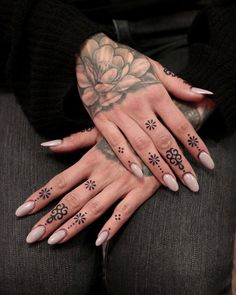 a woman's hands with tattoos and flowers on them