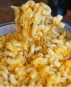 a spoon full of macaroni and cheese being lifted from a bowl