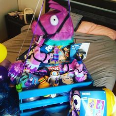 a bed topped with lots of toys next to a bag filled with balloons and other items