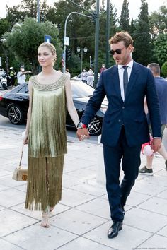 a man in a suit and tie walking with a woman wearing a fringed dress