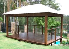 a wooden gazebo sitting on top of a lush green field