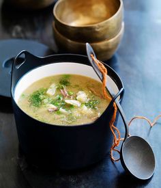 a bowl filled with soup sitting on top of a table next to two spoons