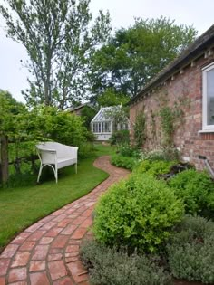 a brick house with a white bench in the front yard