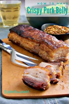 a wooden cutting board topped with meat next to a knife and fork