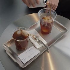 a tray with drinks on it and someone pouring something into the cup from a spoon