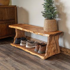 a wooden bench with shoes on it and a potted tree in the corner next to it