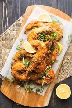 fried shrimp on a cutting board with lemon wedges