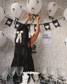 a woman standing in front of white balloons with black and white decorations on the wall