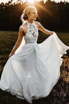 a woman in a white dress is walking through the grass