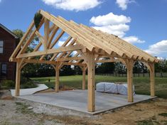 a large wooden structure sitting in the middle of a field next to a building with a tarp covering it