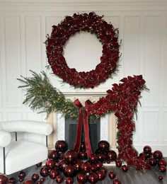 a fireplace decorated for christmas with red balls and greenery