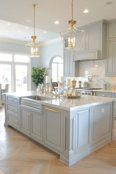 a large kitchen with an island and two chandeliers hanging from it's ceiling