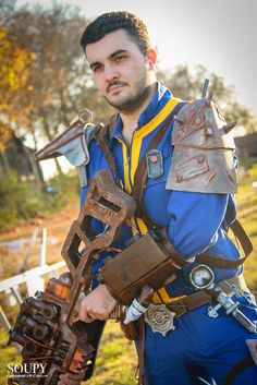 a man dressed in costume holding a giant wrench and an old rusty tool belt