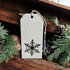 a white tag with a snowflake on it sitting next to pine cones