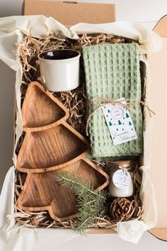 a box filled with wooden spoons and other items next to a cup on top of a table