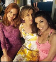 three women posing for the camera in front of a table