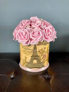 pink roses in a gold tin container on a leather bench