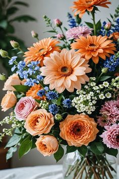 a vase filled with lots of different colored flowers on top of a white table cloth