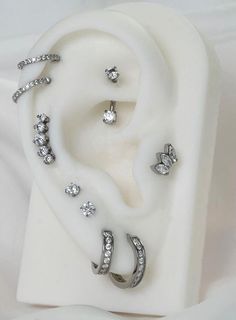 three pairs of ear piercings sitting on top of a white surface