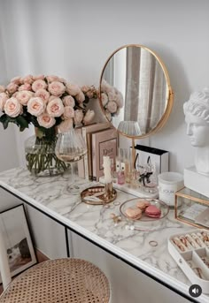 a vanity with flowers, makeup and other personal care items on it next to a mirror