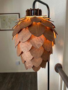 a lamp made out of wooden leaves on a metal pole with a light bulb turned on