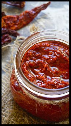 a jar filled with red sauce sitting on top of a table